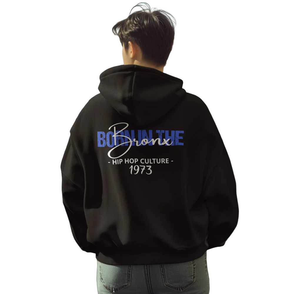 Person wearing a black hoodie with text on the back, standing on a city street.