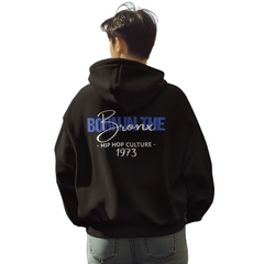 Person wearing a black hoodie with text on the back, standing on a city street.